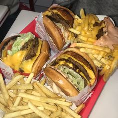 four cheeseburgers and fries on a red tray