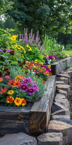 a garden filled with lots of colorful flowers next to rocks and trees in the background