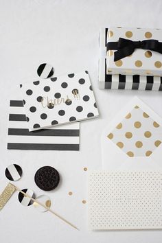 black and white polka dot envelopes with gold foil dots on them, along with some confetti