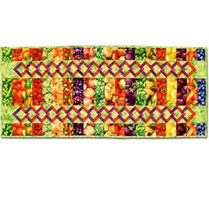 a multicolored table runner with fruit and vegetables on it