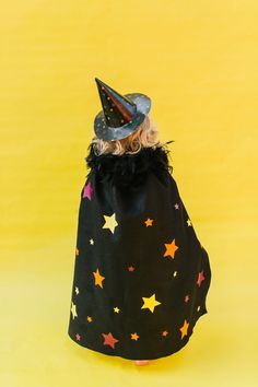 a small dog wearing a witches hat with stars on it's back, sitting in a black bag