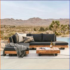 a couch and coffee table on a patio with mountains in the background