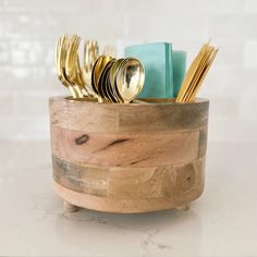 a wooden cup with gold forks and spoons in it