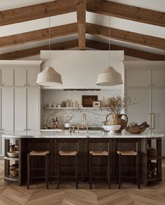 an open kitchen with white cabinets and wooden beams, two hanging lights above the island