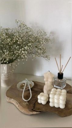 a vase with flowers and candles sitting on a wooden tray next to a candle holder