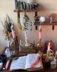 an open book sitting on top of a wooden table next to candles and other items