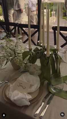 the table is set with white flowers and place settings for guests to sit down at