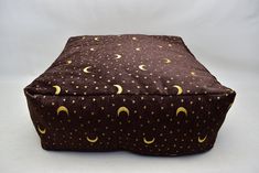 a brown and yellow square ottoman cover with stars and crescents on it, against a white background