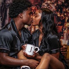 a man and woman kissing while holding a coffee mug