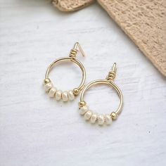 Add a bit of luxury to your look with Aiden Gold & Pearl Luster Beaded Hoops. Small and stylish, these tiny hoops are crafted from 14k gold filled and embellished with pearl luster seed beads. Elevate your style and experience luxury every time you wear them! 14k Gold Filled wire Pearl Luster Miyuki Seed Beads Approximately .625" Diameter Includes Silicone Backing Nut Sent in a Ribboned Gift Box with Polishing Cloth Handmade in Montana 14k Gold-filled Tiny Beaded Earrings, Elegant Gold Earrings With Tiny Beads, Gold Small Hoop Earrings With Tiny Beads, Gold Adjustable Small Hoop Pearl Earrings, Adjustable Gold Beaded Earrings, Handmade Gold Pearl Beaded Earrings, Gold Wire Wrapped Pearl Hoop Earrings, Everyday Gold Wire Wrapped Pearl Earrings, Adjustable Beaded Pearl Earrings