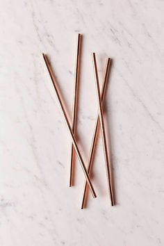 three copper straws on a white marble surface