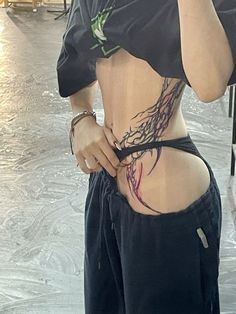 a woman with tattoos on her back holding a cell phone up to her ear and wearing black shorts