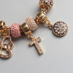 Clara Charm Bracelet The Clara Charm Bracelet brings together elegance and personality in a single, beautifully designed accessory. This bracelet features a series of stunning charms, including hearts, a cross, and dazzling crystals, all carefully arranged on a high-quality alloy chain. The delicate blend of pink and silver or gold accents creates a versatile piece that adds a touch of sophistication to any outfit. Whether you're dressing up for a special occasion or adding some sparkle to your everyday look, the Clara Charm Bracelet is the perfect accessory to express your unique style. Details: - Material: High-quality alloy with crystal accents- Length: 19.5 cm- Weight: 28.24g- Features a variety of charms, including hearts and a cross- Available in silver and gold finishes- Perfect for Gold Rhinestone Bracelets As Gift, Gold Rhinestone Bracelets For Gifts, Gold Bracelets With Rhinestones For Gifts, Gold Alloy Crystal Bracelet As A Gift, Gold Alloy Crystal Bracelet For Gift, Elegant Cross Metal Bracelets, Elegant Metal Cross Bracelet, Elegant Cross-shaped Metal Bracelet, Elegant Gold Crystal Charm Bracelet