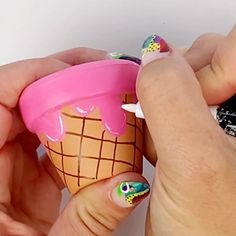 a woman is holding an ice cream cone with colorful designs on her nails and it's in the shape of a cup