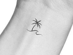 a small palm tree tattoo on the back of a woman's left arm,