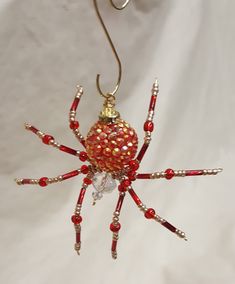 a red and gold spider ornament hanging from a hook