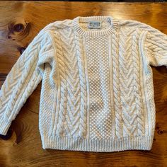 a white sweater sitting on top of a wooden floor