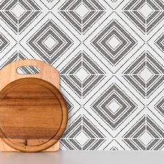 a wooden cutting board sitting on top of a counter next to a wallpaper pattern