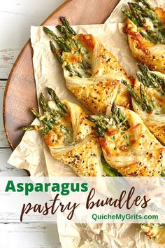 A serving board lined with parchment paper and several asparagus pastry bundles. Asparagus Phyllo Wraps, Alfredo Asparagus Bundles, Phyllo Wrapped Asparagus, Asparagus Wrapped In Puff Pastry, Pastry Wrapped Asparagus, Puff Pastry Asparagus, Asparagus Pastry, Mozzarella Rolls, Asparagus Puff Pastry Bundles