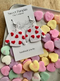 heart shaped candy hearts are on a plate next to a card with the name sweet pumpkin clay company