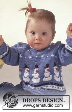 a baby sitting on the floor wearing a blue sweater