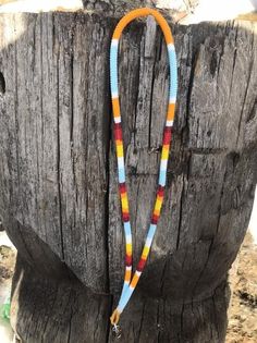 a multicolored beaded necklace is hanging on a piece of wood