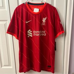 a red liverpool shirt hanging on a door