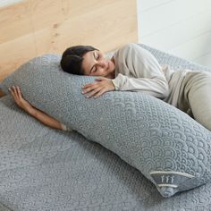 a woman laying on top of a large pillow