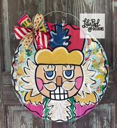 a paper plate with an image of a santa clause on it's face is hanging from a wooden door