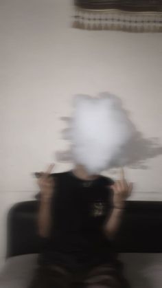 a blurry photo of a person sitting on a couch holding something in front of their face