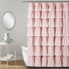 a pink shower curtain with ruffles on it in front of a white bath tub