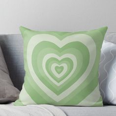 a green heart shaped pillow sitting on top of a couch