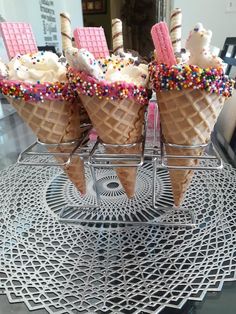 three ice cream cones with sprinkles and candy on top are sitting on a wire rack