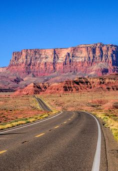 an empty road in the desert with mountains in the background