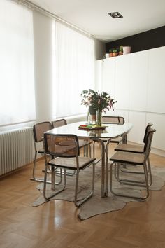 a dining room table with four chairs and a potted plant on top of it