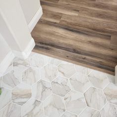 a bathroom with wood flooring and white marble tiles on the walls, along with a green plant