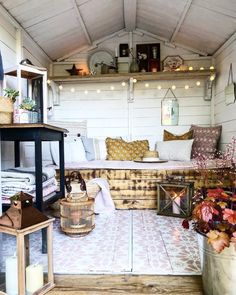 an outdoor room with lots of furniture and lights on the ceiling, along with potted plants