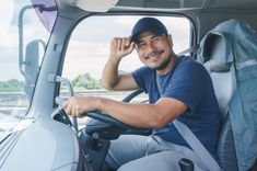 a man sitting in the driver's seat of a truck smiling at the camera