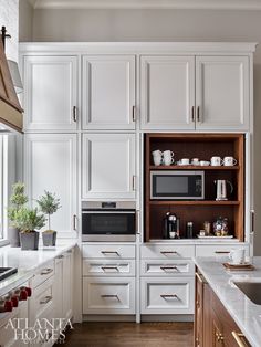 a kitchen with white cabinets and wood flooring is pictured in this image, there are two microwaves on the left side of the cabinet