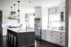 a kitchen with white cabinets and gray island