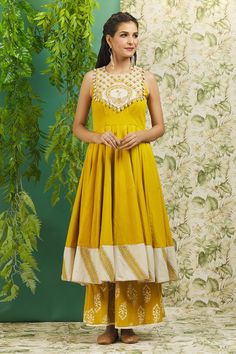 Mustard yellow anarkali with mirror and thread embroidery on the yoke and a contrast stripe pattern trim at the hem. Comes with printed palazzo.
Components: 2
Pattern: Embroidery
Type Of Work: Mirror and Thread
Neckline: Scoop
Sleeve Type: Sleeveless
Fabric: Cotton
Color: Yellow
Other Details: 
Yoke with shell drops on the edge
Gota patti trim on the border
Cutout detail at the back
Closure: Back loop button
Occasion: Wedding - Aza Fashions Yellow Anarkali, Yellow Mirror, Embroidery Mirror, Embroidered Anarkali, Fashion Courses, Palazzo Set, Pattern Embroidery, Cotton Embroidery, Thread Embroidery