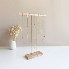 a white vase filled with flowers next to a jewelry rack on top of a table