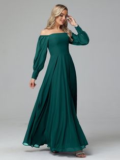 a woman wearing a green dress with long sleeves and an off the shoulder neckline