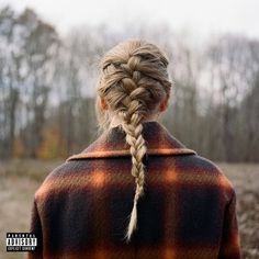 a woman with braids standing in front of a field and looking off into the distance