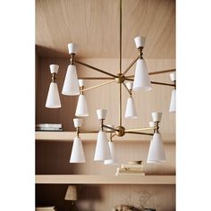 a chandelier with white glass shades hanging from it's brass frame and wooden shelves