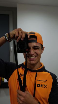 a man holding up a camera to take a selfie with his hat over his head