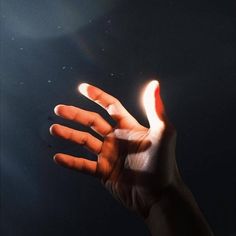 a person's hand reaching up into the air with their light shining on them