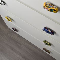 a white dresser with toy cars on the drawers