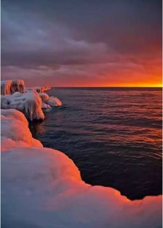 the sun is setting over some ice covered water