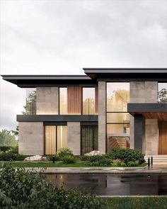 a modern house with lots of windows on the front and side of it, surrounded by greenery